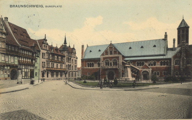 Eine alte Ansichtskarte zeigt den Burgplatz in Braunschweig, Deutschland, mit einer Gruppe von Gebäuden, einer Statue auf einem Sockel, Menschen auf dem Boden, Pflanzen, Gras und einem bewölkten Himmel.