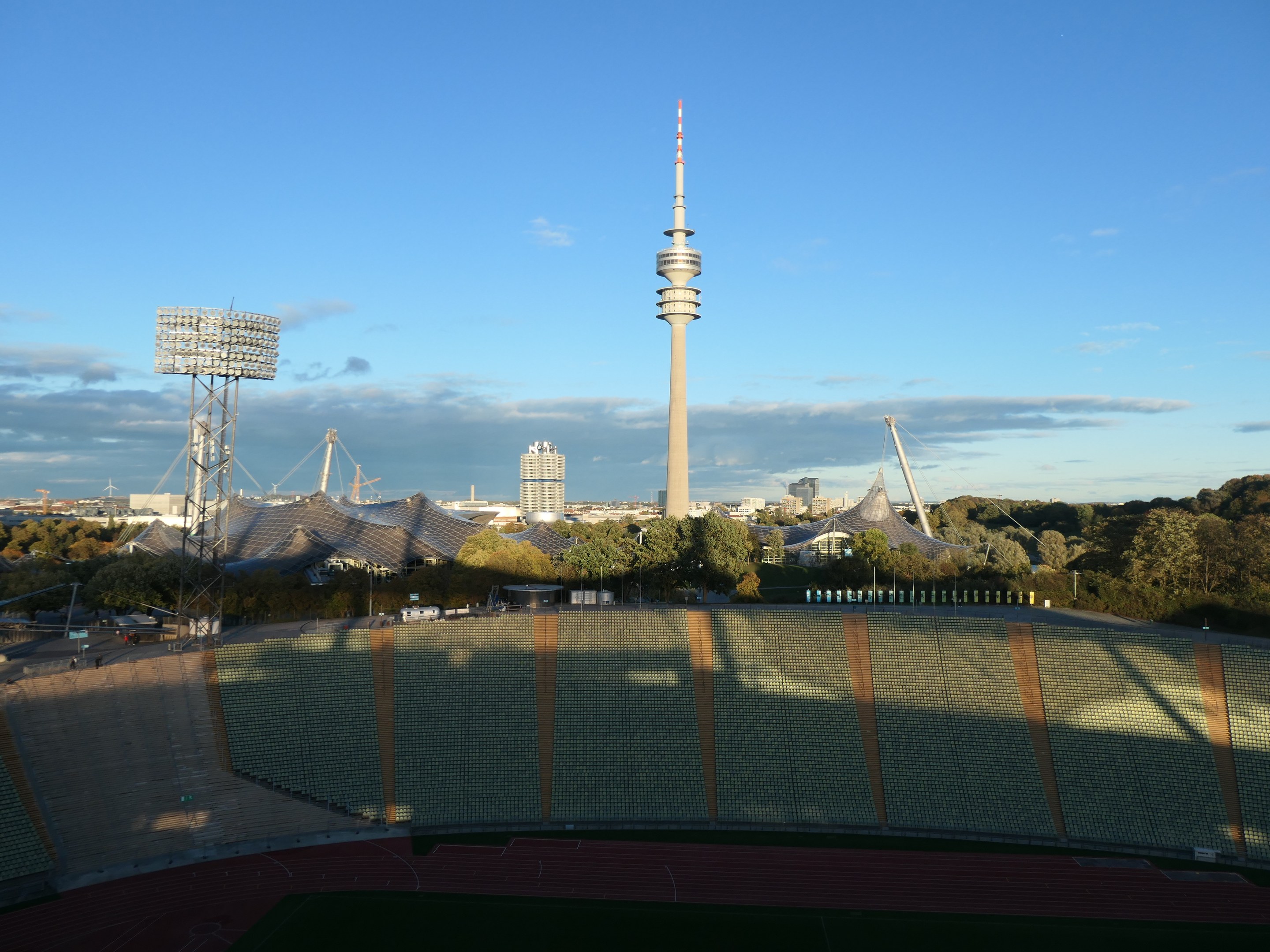 Olympiastadion in Berlin, Deutschland, mit dem Fernsehturm im Hintergrund, umgeben von Bäumen, Gebäuden und Lichtern.