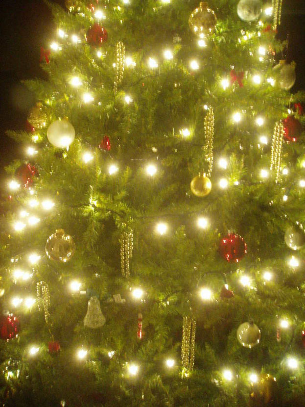 Ein Weihnachtsbaum mit Lichtern, Kugeln und verschiedenen Deko-Elementen.