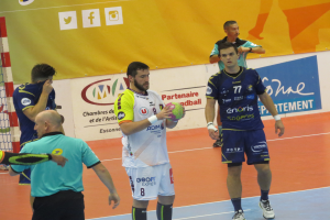 Eine Gruppe von Männern steht auf einem Futsal-Platz, einer hält den Ball, daneben ein Tor und im Hintergrund Banner.