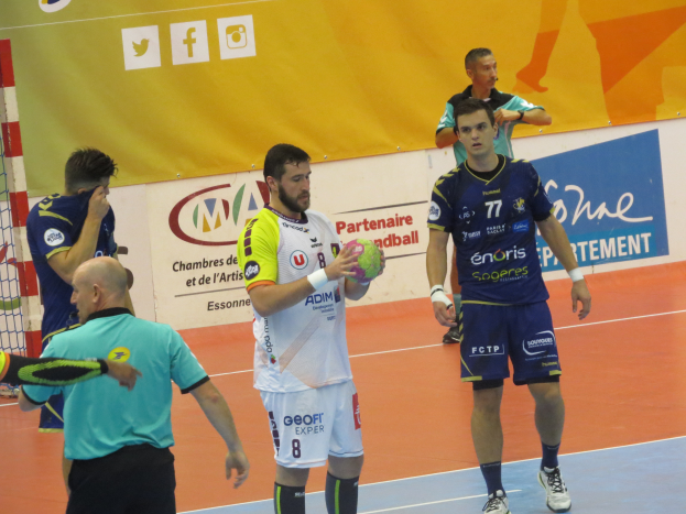 Eine Gruppe von Männern steht auf einem Futsal-Platz, einer hält den Ball, daneben ein Tor und im Hintergrund Banner.