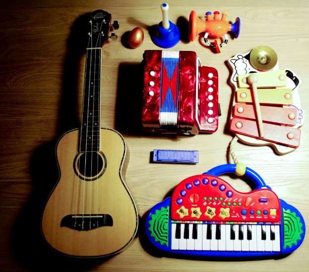 Ein Tisch mit einer Gitarre, Xylophon, Mundharmonikas, einem musikalischen Piano, einem Spielzeug, einem Plastik-Ei und einem Horn.