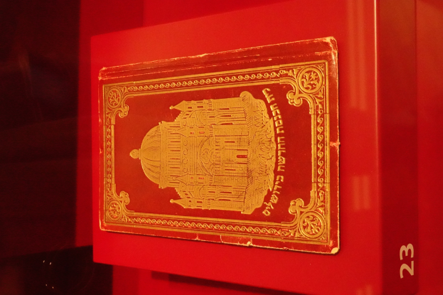 Ein roter Karton mit einer goldenen Karte darauf, der Text, ein Bild und eine Zahl auf dem Karton enthält.