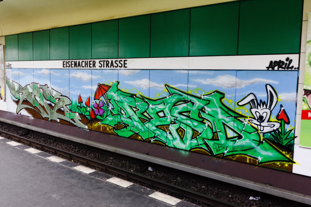 Ein Bahnsteig auf der linken Seite mit einer bunten, lebhaften Graffitiwand auf der rechten Seite.