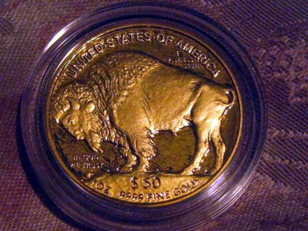 Eine gold- und braune Münze mit der Aufschrift "The United States Of America" darauf, die auf einer braunen Teppichfläche liegt.