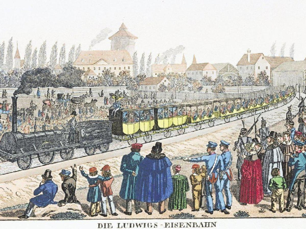 Gruppe von Menschen um einen Zug auf Schienen mit einigen Passagieren im Zug und anderenstehenden draußen, vor Häusern und Bäumen im Hintergrund; Text unten lautet "Ludwigs-Eisenbahn, die erste Bahnstation in Deutschland".