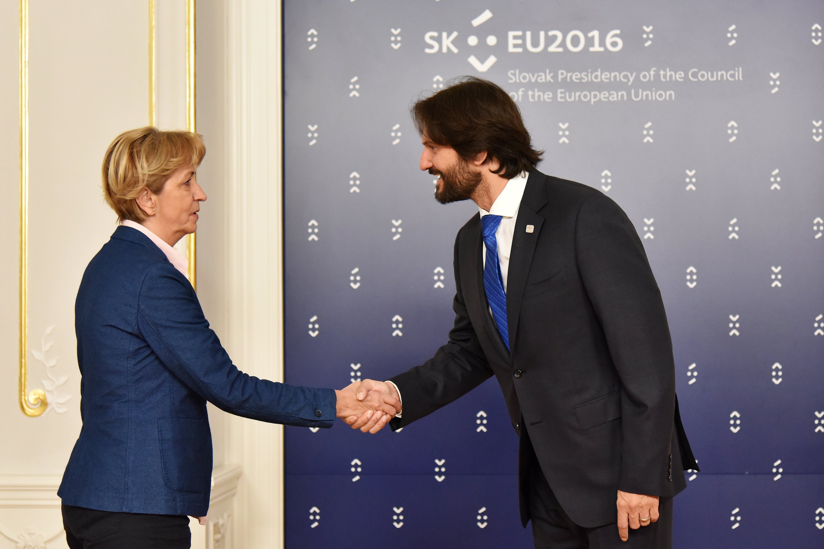 Bundeskanzlerin Angela Merkel und Bundespräsident Joachim Gauck geben sich die Hand vor einem Banner mit der Aufschrift "EU-Gipfel", beide lächeln.