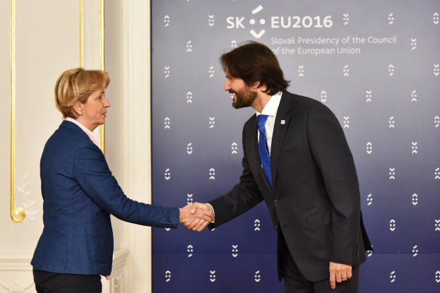 Bundeskanzlerin Angela Merkel und Bundespräsident Joachim Gauck geben sich die Hand vor einem Banner mit der Aufschrift "EU-Gipfel", beide lächeln.