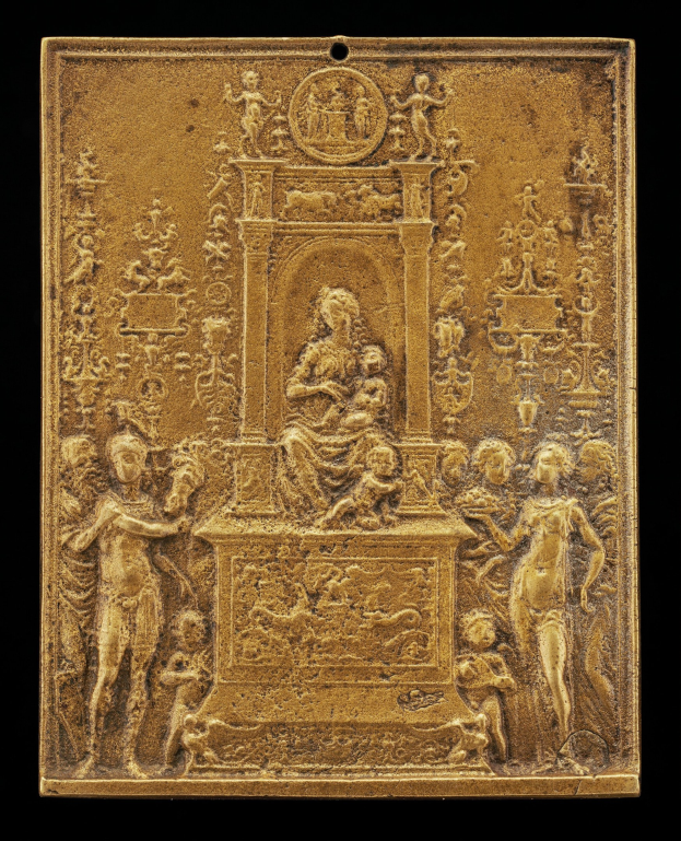 Goldene Plakette mit detaillierter Skulptur einer Frau in einem wallenden Kleid und einem Mann in Anzug und Krawatte auf schwarzem Hintergrund, eingerahmt von einem goldenen Rand.