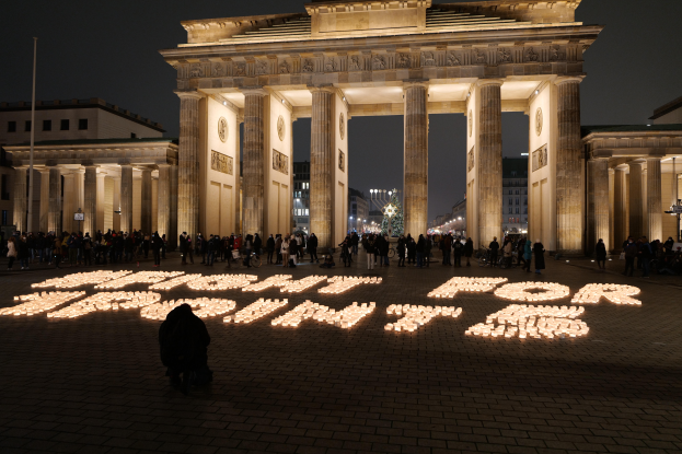 Eine Gruppe von Menschen steht vor dem beleuchteten Reichstagsgebäude in Berlin, Deutschland, mit den Worten "Kämpfe für die Freiheit" im Vordergrund.