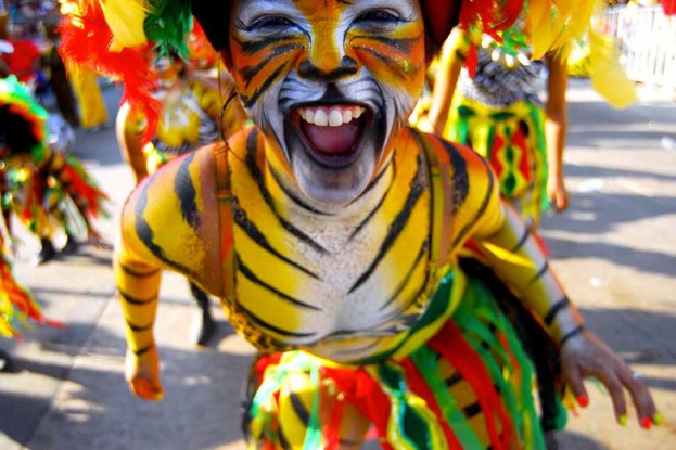 Eine Gruppe von Menschen in bunten Kostümen und Schminke auf einem Karneval, mit einer Frau in einem Tigerkostüm im Vordergrund und einem unscharfen Hintergrund.