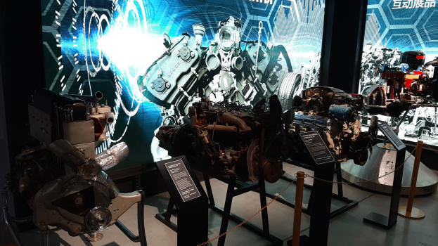 Ein Raum voller verschiedener Motorenarten auf Display, mit Maschinen auf Ständern und Texttafeln im Hintergrund, mit einem prominenten Rad.