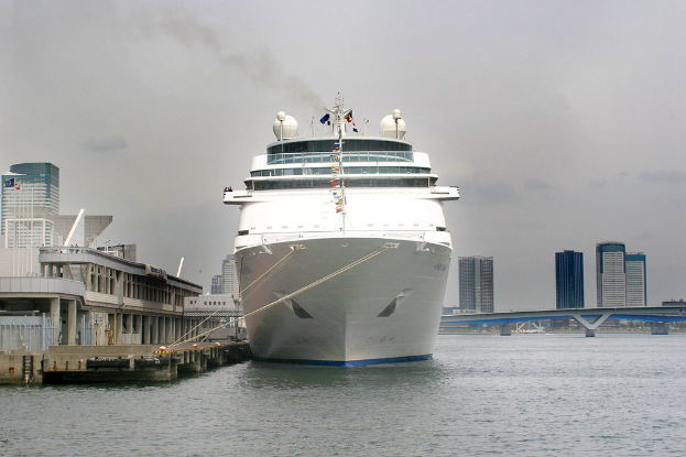 Ein auf dem Wasser schwimmendes Schiff neben einer Brücke und zahlreichen Gebäuden.