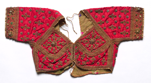 Rotes Oberteil mit goldener Stickerei mit detaillierten Designs, vor einem weißen Hintergrund.