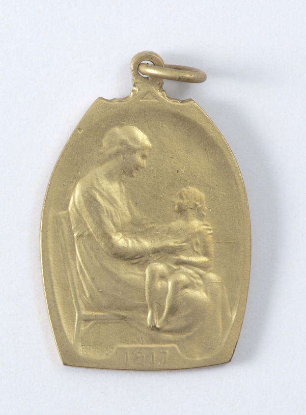 Goldmedaille mit Relief einer Frau in weißem Kleid mit Haarknoten, die ein Kind hält, beide schauen sich sanft und neugierig an, beschriftet mit "Mutter und Kind."