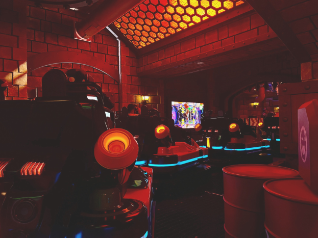 Ein hell erleuchteter Raum voller verschiedener Arcade-Videospielautomaten und -geräte, einschließlich Bildschirme, Lichter und Rohre.