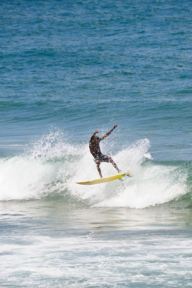 Ein Mann steht auf einem Surfbrett und reitet eine Welle.