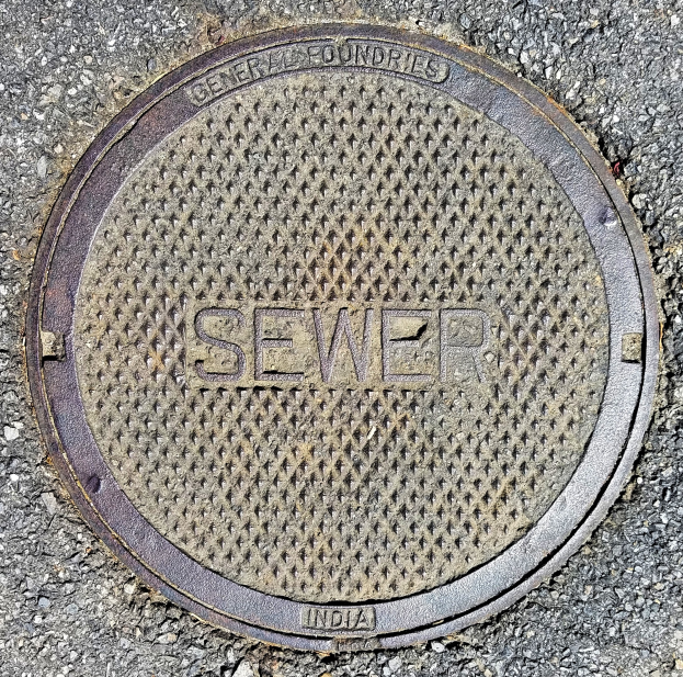 Metallschachtdeckel auf der Straße mit der geprägten Aufschrift "Kanal"