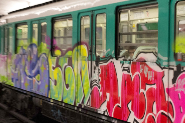 Ein Zug auf Eisenbahnschienen mit zwei Personen darin und Graffiti an seiner √Ąu√üeren.