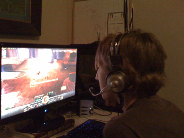 Eine Person mit Kopfhörern spielt ein Videospiel auf einem Monitor.