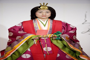 Eine Frau in einem traditionellen japanischen Kimono steht selbstbewusst auf einem Laufsteg und trägt ein leuchtend rotes und grünes Kleid mit kunstvollen Mustern und ihr Haar ist ordentlich zurückgebunden.