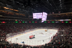 Ein Hockey-Spiel in der Gila River Arena mit Zuschauern auf den Tribünen und Fahrzeugen auf dem Eis.