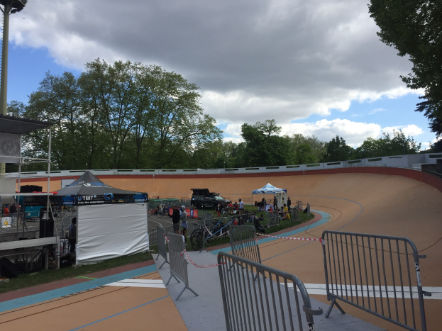 Gruppe von Radfahrern auf einer Schmutz BMX-Strecke bei den UCI BMX-Weltmeisterschaften 2018, mit Zuschauern, Zelten und Fahrzeugen im Hintergrund.