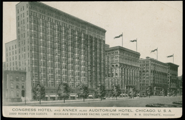 Ein Schwarz-Weiß-Foto des Congress Hotel und des Annex Auditorium Hotel in Chicago, Illinois, ein großes Gebäude mit vielen Fenstern, umgeben von Bäumen und Fahnen mit Stangen, mit einem klaren Himmel im Hintergrund und Text unten auf dem Bild.