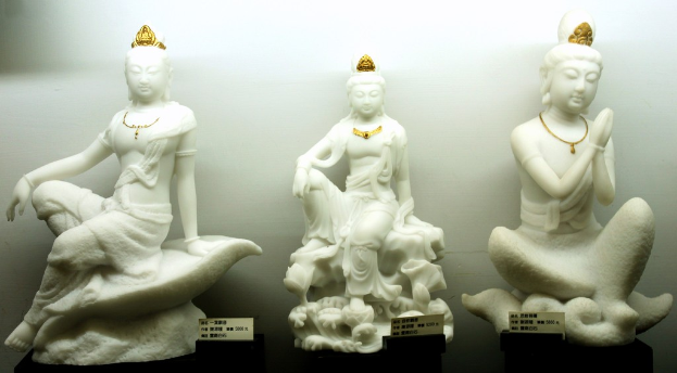 Mehrere Statuen oder Idole sind vor einer Wand positioniert.