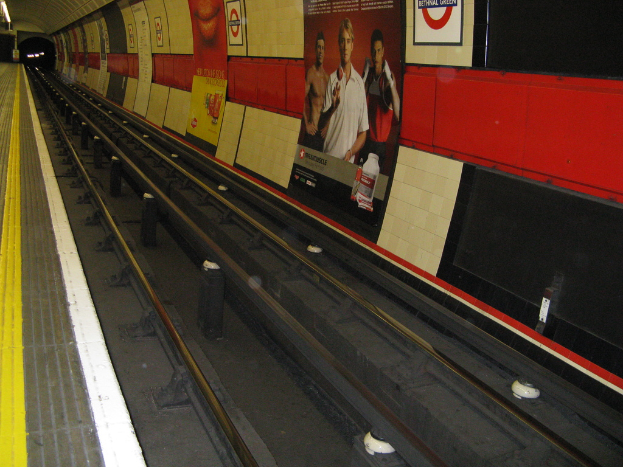 Eine Bahnschiene mit Plakaten an der benachbarten Wand.