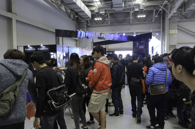 Menschen vor einer Menge an einer Gaming-Messe, mit Brettern, Lichtern und Rohren im Hintergrund.