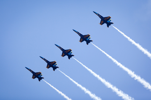 Mehrere Jets setzen blauen und gelben Rauch gegen einen blauen Himmel ab.
