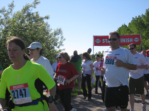 Eine Gruppe von Kindern läuft bei einem Marathonrennen mit einer roten Fahne und Bäumen im Hintergrund.