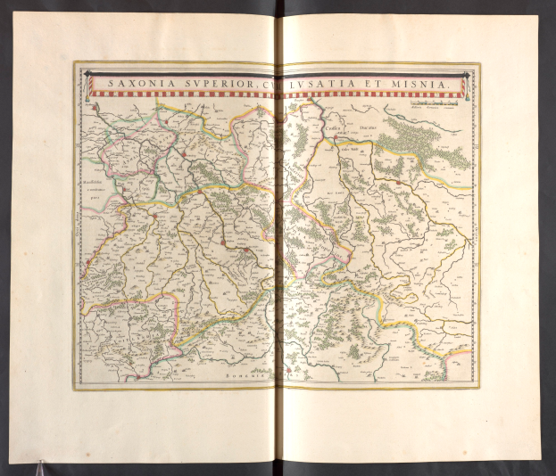 Ein aufgeschlagenes Buch mit einer detaillierten Karte von Sachsen, die die Provinzen und Städte hervorhebt, vor schwarzem Hintergrund.