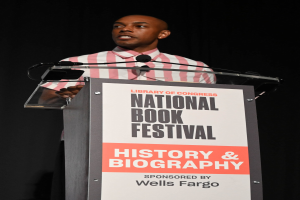 Ein Mann steht an einem Rednerpult mit einem Mikrofon bei einer Abendveranstaltung mit dem Titel "National Book Festival Geschichte & Biografie".