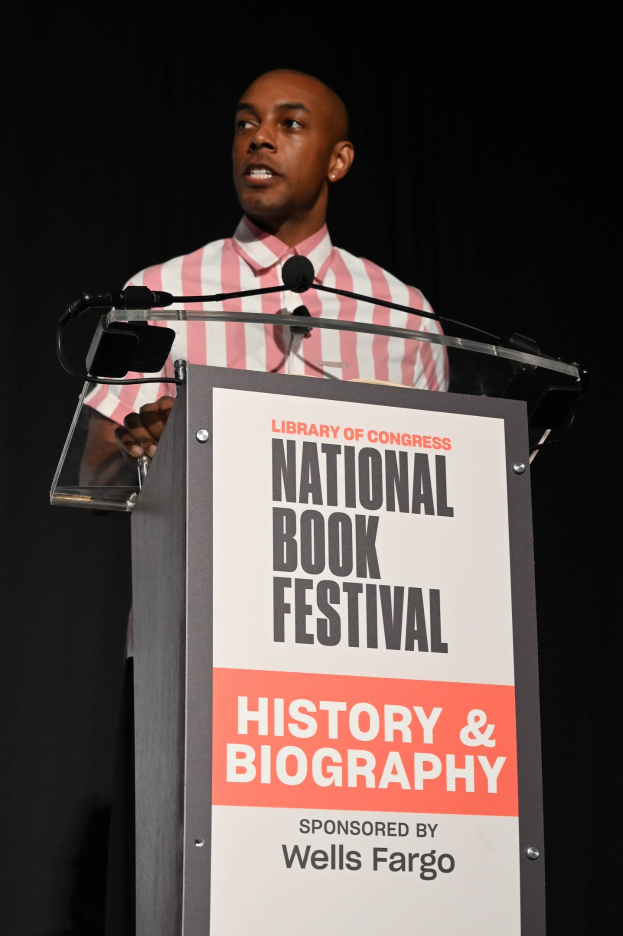 Ein Mann steht an einem Rednerpult mit einem Mikrofon bei einer Abendveranstaltung mit dem Titel "National Book Festival Geschichte & Biografie".