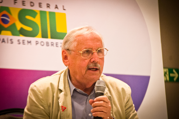 Eine Person spricht in ein Mikrofon mit einem Banner im Hintergrund, auf dem das Wort 'Bundes' steht.